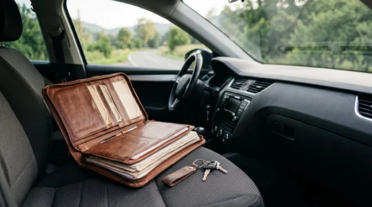 Porte-documents en cuir ouvert sur le tableau de bord d'une voiture avec des papiers rangés proprement